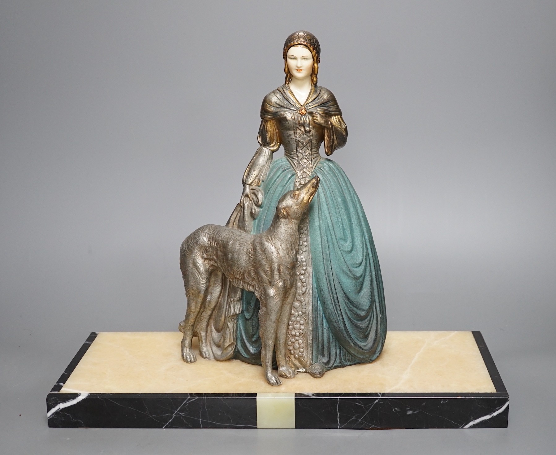 An Art Deco cold painted spelter and composition figure of a lady with a dog, signed R Miandres, 38cm wide